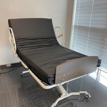 Hospital bed with black mattress and rails.